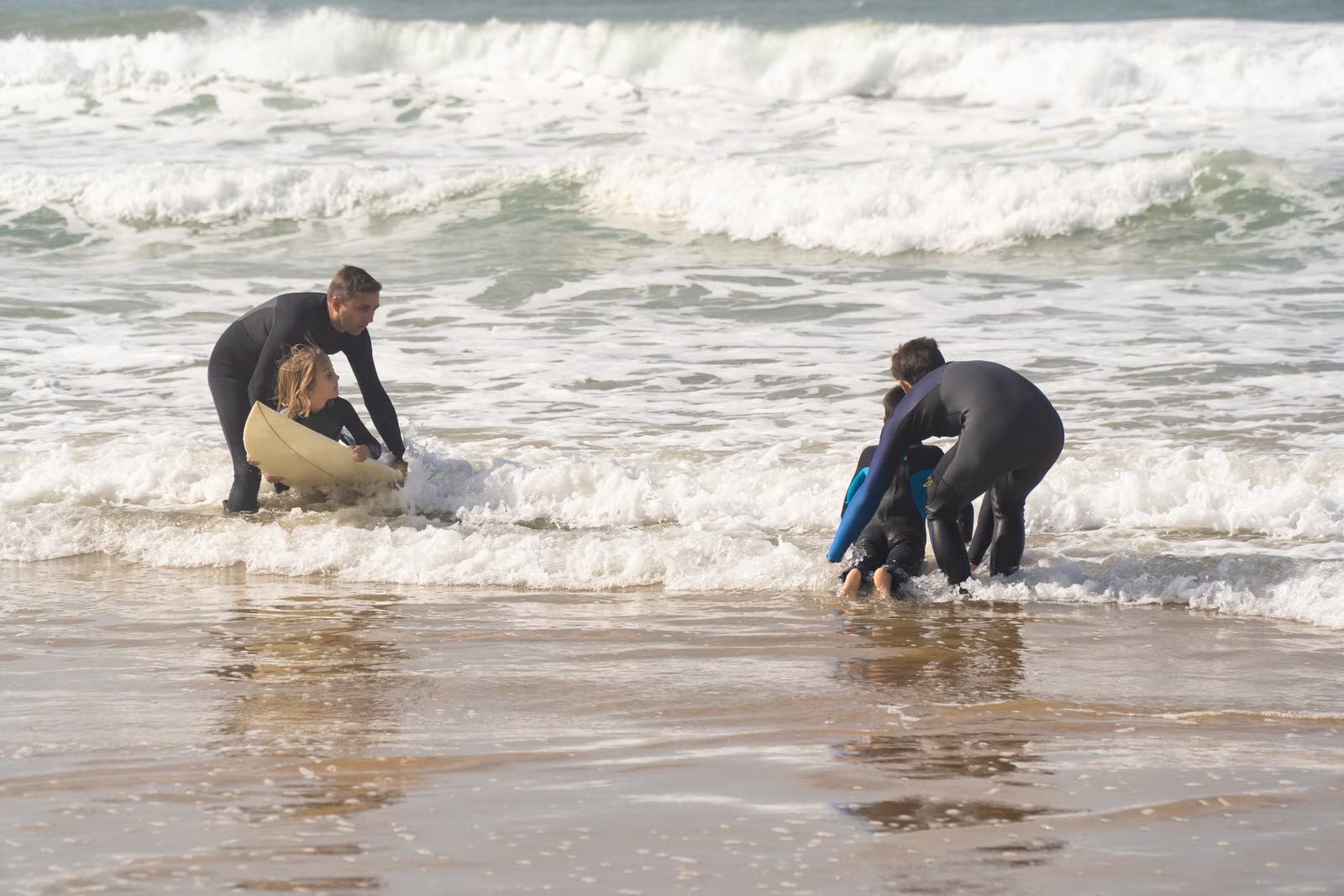 Enfants en cours de surf avec leurs moniteurs